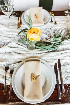 wedding table decorated by plates, knives and forks, candle, moss, flowers roseの写真素材