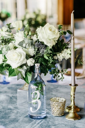 wedding table decorated by plates, knives and forks, candle, moss, flowers roseの写真素材
