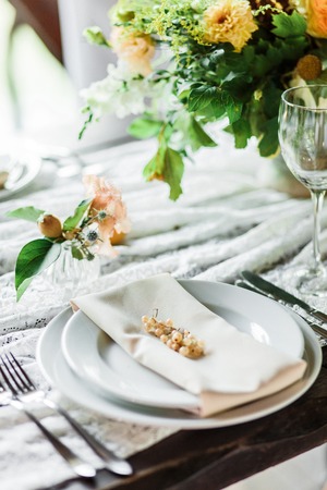 wedding table decorated by plates, knives and forks, candle, moss, flowers roseの写真素材