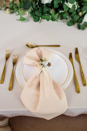 wedding table decorated by plates, knives and forks, candle, moss, flowers roseの写真素材