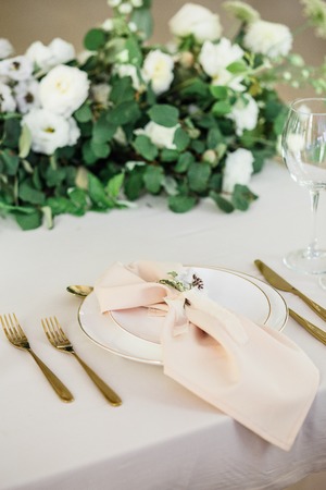 wedding table decorated by plates, knives and forks, candle, moss, flowers roseの写真素材