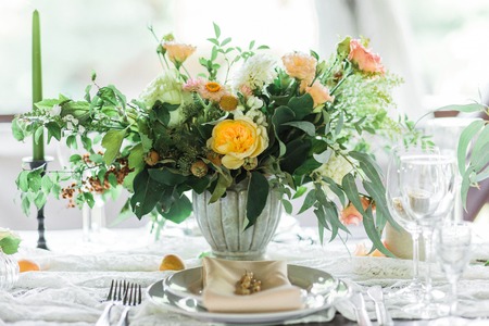wedding table decorated by plates, knives and forks, candle, moss, flowers roseの写真素材
