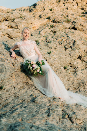 Stunning bride in beautiful wedding dress on rock background.の写真素材