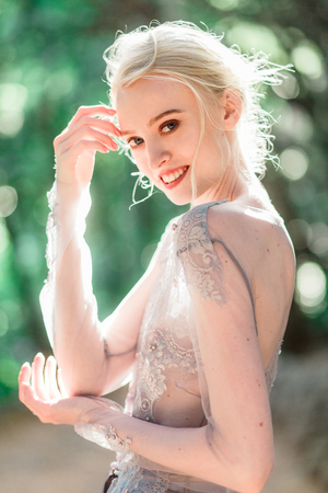 Stunning bride in beautiful wedding dress on natural background. The stunning young bride is incredibly happy. Wedding day. beautiful bouquetの写真素材