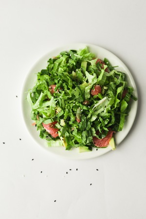 Healthy green vegan salad with grapfruit in plate on white backgroundの写真素材