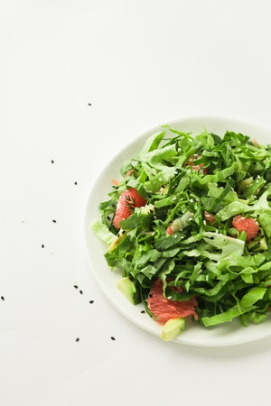 Healthy green vegan salad with grapfruit in plate on white backgroundの写真素材