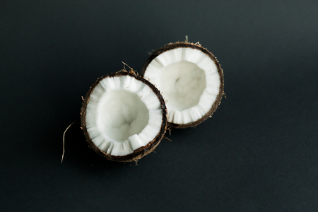 Broken ripe coconut on black background. brown peel and white fleshの写真素材