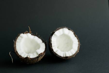 Broken ripe coconut on black background. brown peel and white fleshの写真素材