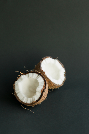 Broken ripe coconut on black background. brown peel and white fleshの写真素材