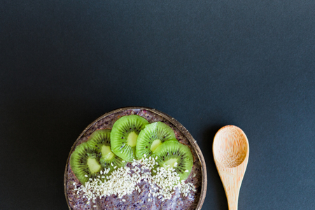 Healthy smoothie with fruits, plate made from coconut shell and wood spoon. Kiwi, banana, black currantの写真素材