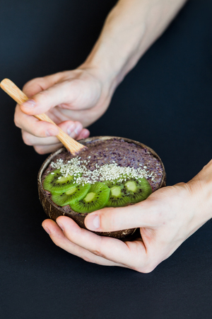 Healthy smoothie with fruits, plate made from coconut shell and wood spoon. Kiwi, banana, black currantの写真素材