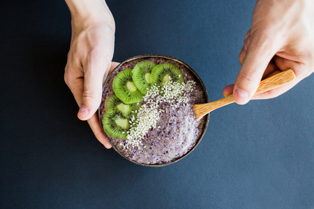 Healthy smoothie with fruits, plate made from coconut shell and wood spoon. Kiwi, banana, black currantの写真素材