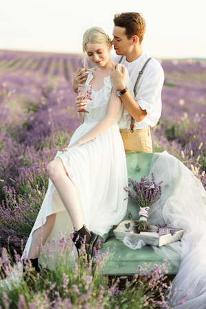Beautiful portrait of bride and groom hug each other tender on sunset in lavander fieldの写真素材