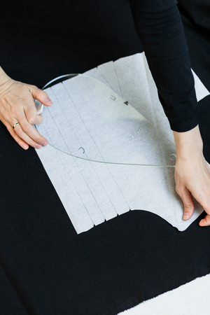 Beautiful seamstress, cut black fabric on the studio floor,draws on fabricの写真素材