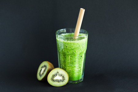 Healthy green smoothie with kiwi and spinach in a glass Cup on a black backgroundの写真素材