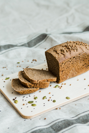 Freshly baked sliced bread on a wooden Board on dark grey fabric with seed