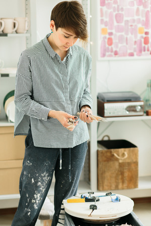 girl potter's holds carving tools on ceramics in her studio