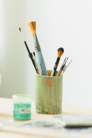 drawing tools in a ceramic glass and paints on a wooden tableの写真素材