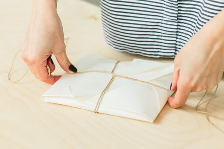 girl packs a gift on a wooden table in a studioの写真素材