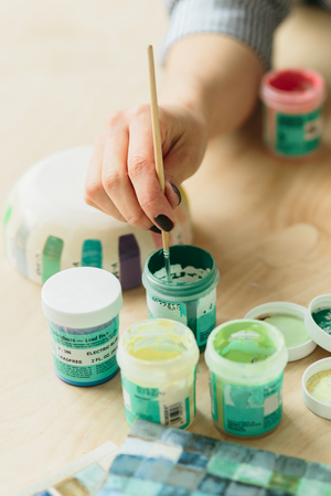 Potter holds the color palette glazes for coating ceramic products on wood tableの写真素材