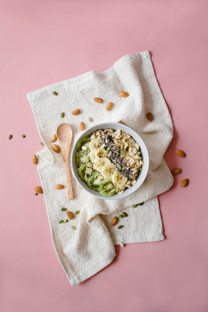 healthy Breakfast of oatmeal with kiwi, banana and chia seed on a white napkin, on pink backgroundの写真素材