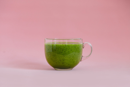 Healthy green smoothie with kiwi and green apple in a glass cup on pink backgroundの写真素材