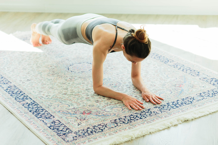 Young attractive smiling woman practicing yoga in a large, bright roomの写真素材