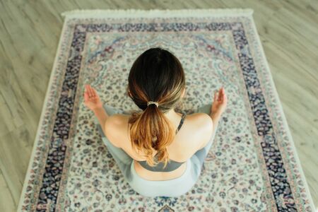 Young attractive smiling woman practicing yoga in a large, bright roomの写真素材