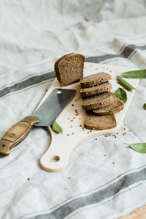 Freshly baked sliced bread on a wooden Board on dark grey fabric with seedの写真素材