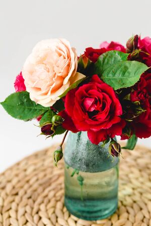 Coloful roses in vase on a nature wicker napkin on white backgroundの写真素材