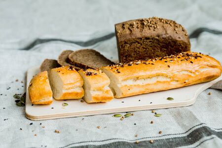Freshly baked sliced bread on a wooden Board on dark grey fabric with seed