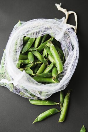 Reusable eco-friendly bag full of fresh seasonal pea pods . Taking care of the environment and...