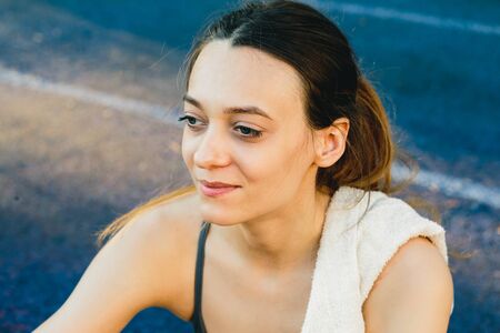 Young woman with a bottle of water after Jogging outdoors in Singapore. She is wearing grey top and a light sports leggingsの写真素材