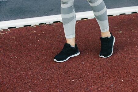 Young woman doing outdoor exercise in new York. She is wearing a grey top and light sport leggings