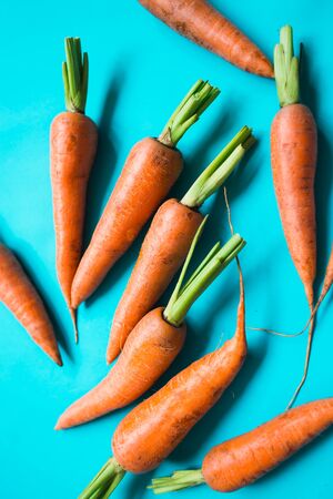 A few fresh carrots on blue background. Rustic style. Farming.の写真素材