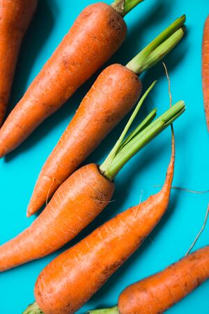 A few fresh carrots on blue background. Rustic style. Farming.の写真素材