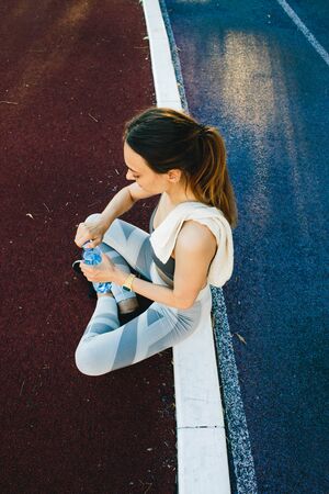 Young woman with a bottle of water after Jogging outdoors in Singapore. She is wearing grey top and...