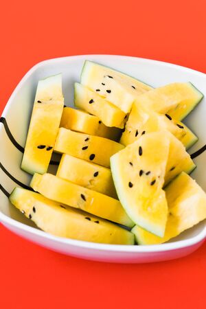 ripe yellow watermelon on red background, summer foodの写真素材