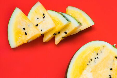 ripe yellow watermelon on red background, summer foodの写真素材