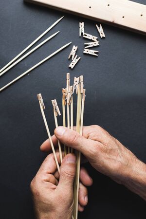 glue together wooden clothespins and sticks, make a holder for photos on a black background
