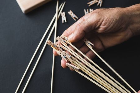 glue together wooden clothespins and sticks, make a holder for photos on a black backgroundの写真素材