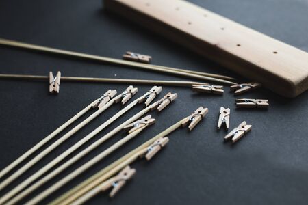 glue together wooden clothespins and sticks, make a holder for photos on a black backgroundの写真素材