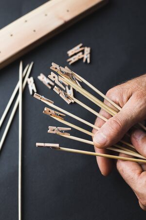 glue together wooden clothespins and sticks, make a holder for photos on a black backgroundの写真素材