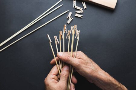 glue together wooden clothespins and sticks, make a holder for photos on a black backgroundの写真素材