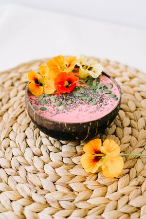 Breakfast in a plate of coconut with nasturtium flowers on natural wicker napkinの写真素材