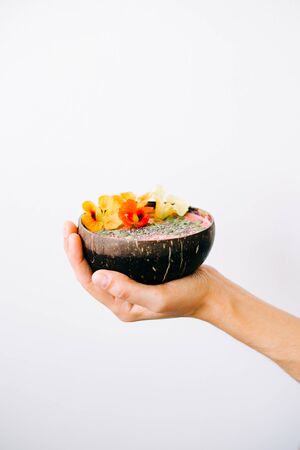 Breakfast in a plate of coconut with nasturtium flowers in hand