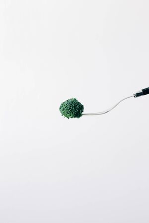 a fork with a green inflorescence of fresh broccoliの写真素材