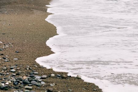 the sea wave arrives on the sandy shore .