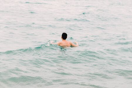 a young guy is swimming in the blue clear water of the ocean. thailandの写真素材