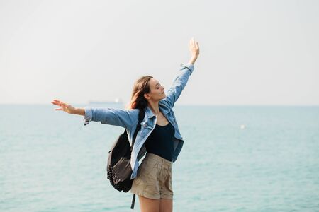 a young girl traveler with a backpack walks barefoot on large stones on the sea coast. summerの写真素材